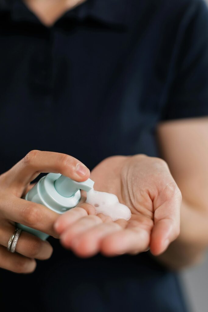 Close-up of hands applying liquid soap from a dispenser for personal care.